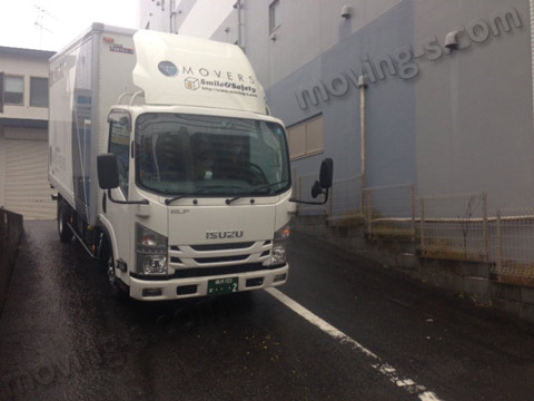 雨の中を東京の引越し現場に向かうトラック